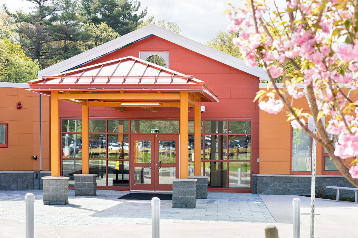 Early childhood education center entrance with orange panels and a timber canopy